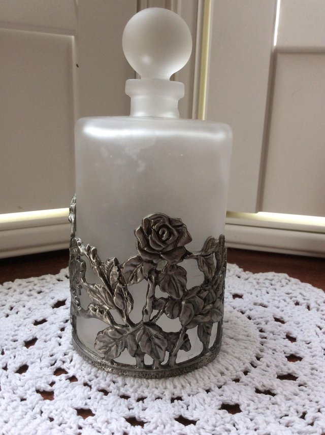 Preview of the first image of Opaque glass perfume bottle with metal flowers.