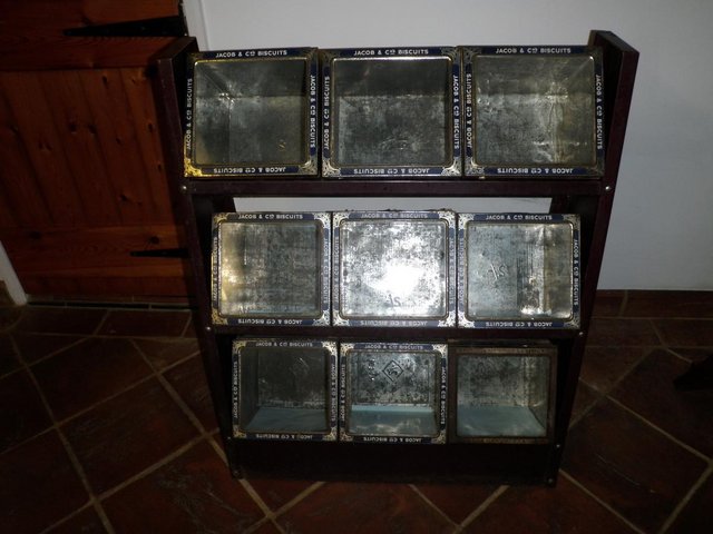 Preview of the first image of NINE BISCUIT TINS with GLASS LIDS IN A DISPLAY STAND.